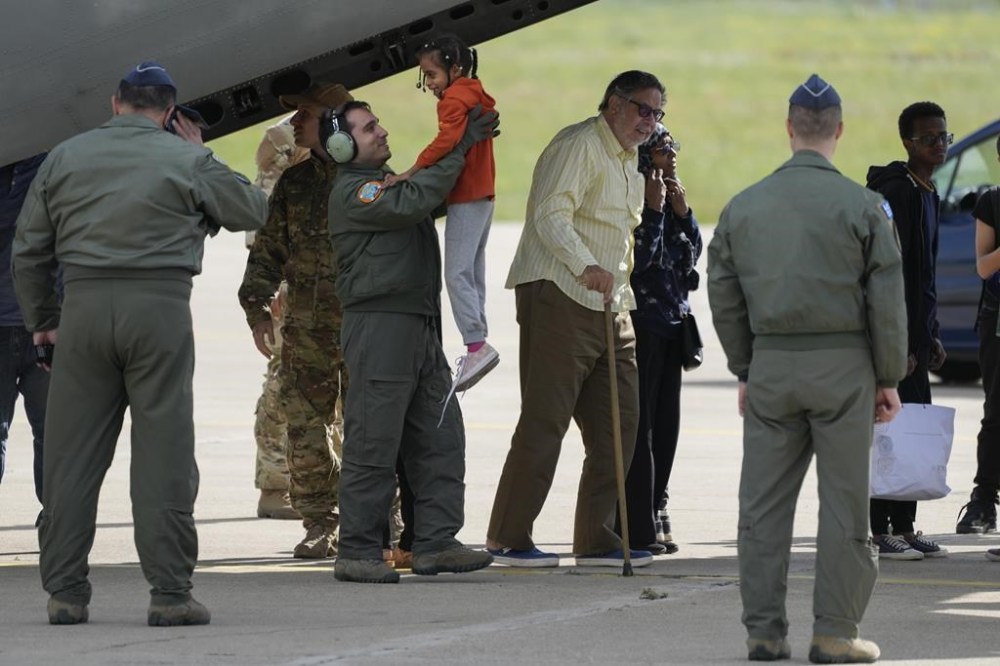 A member of the Greek airforce holds a child as evacuees from Sudan disembark from a military plane at Tanagra air base, north of Athens on Wednesday, April 26, 2023. Sixteen Greeks and one Cypriot arrived in Greece after being evacuated from Sudan. (AP Photo/Thanassis Stavrakis)
