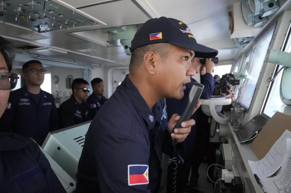 Philippine Coast Guard Petty Officer 3 John Solatre uses the radio on board the BRP Malabrigo to send a message to suspected Chinese militia ships near Philippine-claimed island of Thitu, locally known as Pag-asa island at the South China Sea on Friday April 21, 2023. The move drove out 4 suspected Chinese militia ships as the Philippine Coast Guard asserts the country's territorial claim. (AP Photo/Aaron Favila)