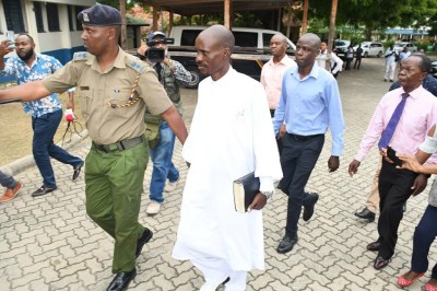 Pastor Ezekiel Odero, center, holds a bible as he is led by police in Mombasa, Kenya, Thursday April 27, 2023. Police in Kenya arrested another popular pastor on the Indian Ocean coast as the number of deaths linked to a cult in the area rose to 103 on Thursday. Odero “is being processed to face criminal charges related to mass killing of his followers”, according to a statement by Interior Minister Kithure Kindiki. (AP Photo/Maarufu Mohamed)