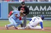 Los Angeles Dodgers' Freddie Freeman, right, steals second as St. Louis Cardinals second baseman Tommy Edman, left, takes a late throw and second base umpire Mike Muchlinski watches during the first inning of a baseball game Saturday, April 29, 2023, in Los Angeles. (AP Photo/Mark J. Terrill)