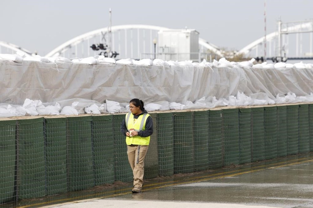 A city worker walks along the HESCO sand barriers along River Drive between Iowa and Perry Streets, Friday, April 28, 2023, in Davenport, Iowa. The Upper Mississippi River will rise to near record-high levels as it flows through Wisconsin and Iowa, but officials said Thursday they expected to hold back floodwaters with a combination of flood walls, temporary barriers and wetlands, especially if dry weather continues. (Nikos Frazier/Quad City Times via AP)