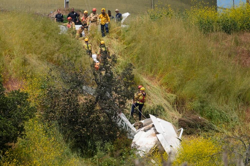 Los Angeles City Fire Department's Urban Search and Rescue members assist in recovering the pilot's body of a downed Cessna C172 on a steep hill above a home on Beverly Glen Circle in Los Angeles, Sunday, April 30, 2023. Fire department officials said a person was found dead following an intensive search for the single-engine airplane that crashed in a foggy area Saturday night. The plane avoided hitting power lines and a large water tank and, officials said, there was minimal fire. (AP Photo/Damian Dovarganes)