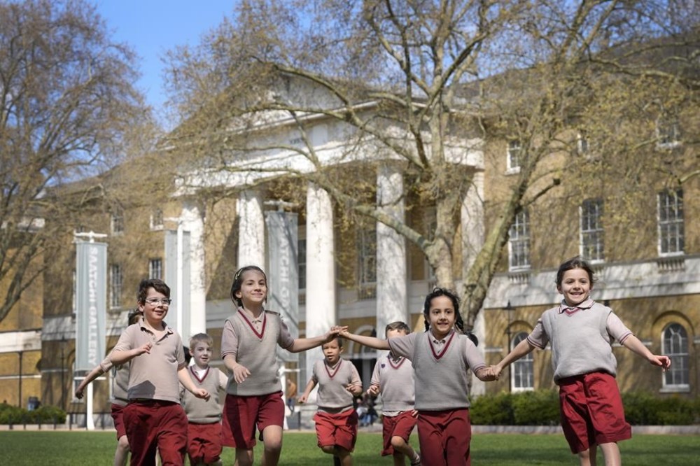 Pupils from Hill House School in London, play on the grass in front of the now Saatchi Gallery, where Britain's King Charles III played sport as a pupil, Thursday, April 20, 2023. King Charles III hasn’t even been crowned yet, but his name is already etched on the walls of Hill House School in London. A wooden slab just inside the front door records Nov. 7, 1956, as the day the future king enrolled at Hill House alongside other notable dates in the school’s 72-year history. (AP Photo/Kirsty Wigglesworth)