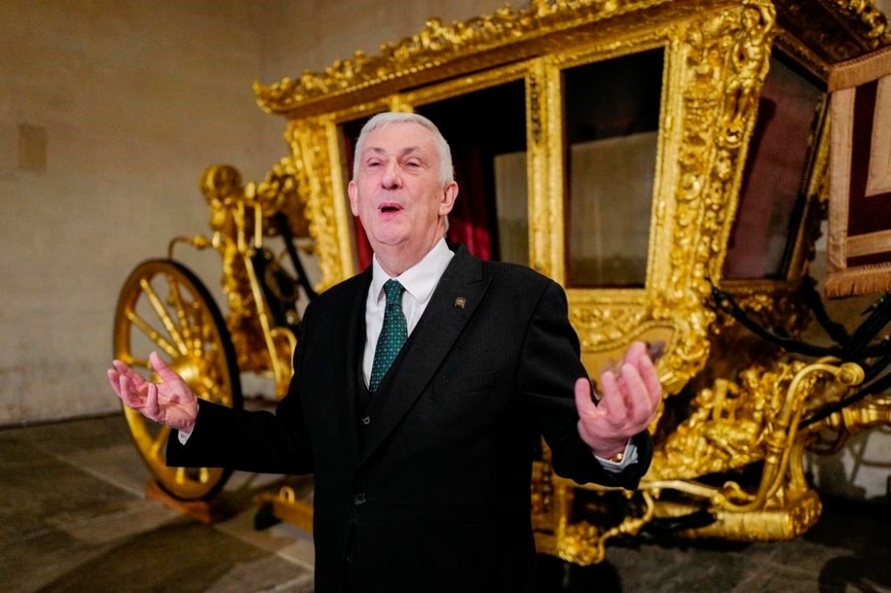 Britain's Speaker of the House of Commons Lindsay Hoyle stands next to the Speaker's State Coach as it returns to Westminster, ahead of the coronation of Britain's King Charles III, in London, Sunday, April 30, 2023. The gilded coach, which was last seen in the historic Westminster Hall in 2005, will be on display once again from 2 May to the Autumn, to commemorate the crowning of King Charles III. (AP Photo/Alberto Pezzali)