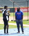 Chicago White Sox's Tim Anderson, left, wears a knee brace as he talks with former teammate and Philadelphia Phillies infielder Josh Harrison after Anderson's rehabilitation workout before a baseball game between the two clubs Wednesday, April 19, 2023, in Chicago. (AP Photo/Charles Rex Arbogast)
