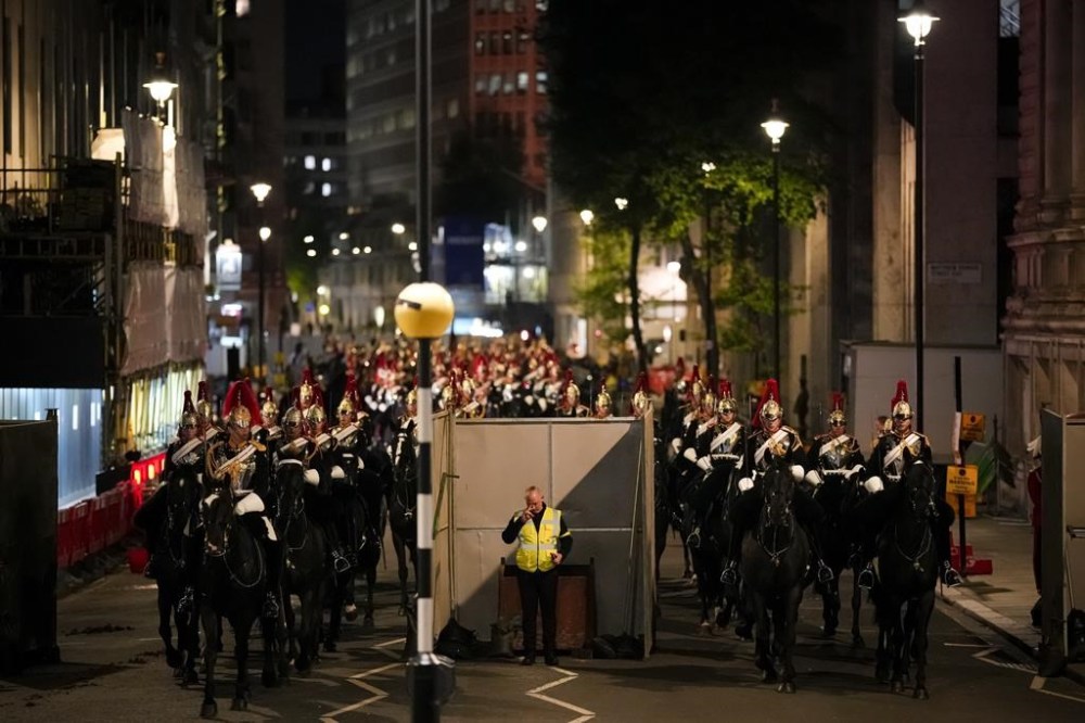 A steward touches his forehead as mounted military prepare to take part in a rehearsal for the Coronation of King Charles III near Westminster Abbey in central London, early Wednesday, May 3, 2023. (AP Photo/Andreea Alexandru)