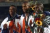 FILE - United States gold medalist Derrick Adkins is flanked by teammate and bronze medalist Calvin Davis, left, and silver medalist Samuel Matete of Zambia, right, after the 400 meter hurdle final at the 1996 Summer Olympic Games in Atlanta, Thursday, Aug. 1, 1996. Calvin Davis, the Olympic bronze medalist in the 400 hurdles at the 1996 Atlanta Games, has died. He was 51. The University of Arkansas, where he went to school, said Davis died Monday, May 1, 2023. No cause of death was given. (AP Photo/Ed Reinke, File)