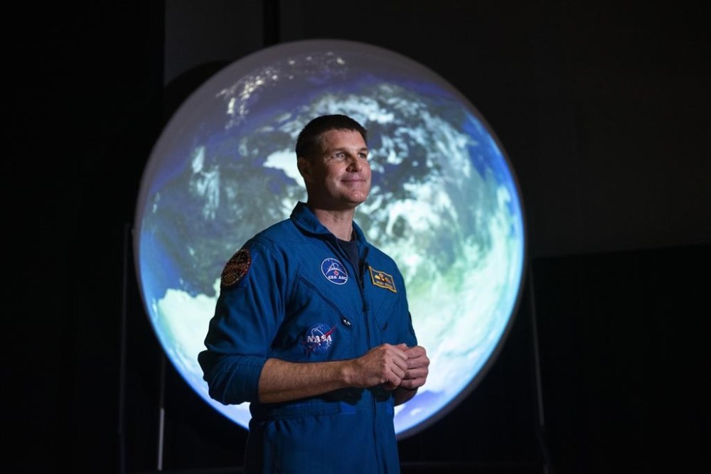 Canadian Space Agency astronaut Jeremy Hansen stands in front of a display as he participates in an interview at the opening of Earth in Focus: Insights from Space, a new exhibition at the Canada Science and Technology Museum in Ottawa, on Friday, Nov. 26, 2021. Before Hansen gets a change to plant Canada's flag on a mission to the moon next year he will carry the Canadian flag at the coronation of the country's new King. THE CANADIAN PRESS/Justin Tang