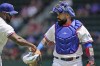 Texas Rangers catcher Sandy Leon, right, right walks on the field before a baseball game against the Arizona Diamondbacks in Arlington, Texas, Wednesday, May 3, 2023. Veteran big league catcher Sandy León changed his uniform to No. 12 this season with the Texas Rangers to remind himself of the worst day of his life. (AP Photo/LM Otero)