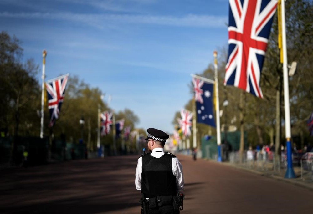 A British police officer stands guard as people line up days before the official coronation of King Charles III near Buckingham Palace along the Mall in London on Wednesday, May 3, 2023. THE CANADIAN PRESS/Nathan Denette