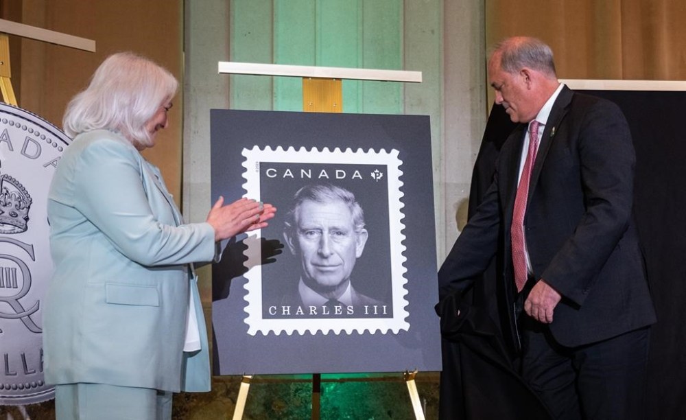 The official stamp is unveiled by Donald Booth, right, Canadian Secretary to the King, right, and Jo-Anne Polak, Senior Vice-President, Corporate and Employee Communication at Canada Post during coronation celebrations in honour of King Charles III in Ottawa, on Saturday, May 6, 2023. THE CANADIAN PRESS/Spencer Colby