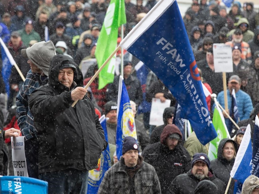 Crab fisherman, Vincent Hearn, waves a UNIFOR Fish, Food, and Allied Workers flag at a rally at the Confederation Building in St. John's, Monday, April 17, 2023. The union that represents crab fishers in Newfoundland and Labrador is keeping the fleet at the wharf, after its members rejected the most recent price offer from the association that represents processors. THE CANADIAN PRESS/Paul Daly