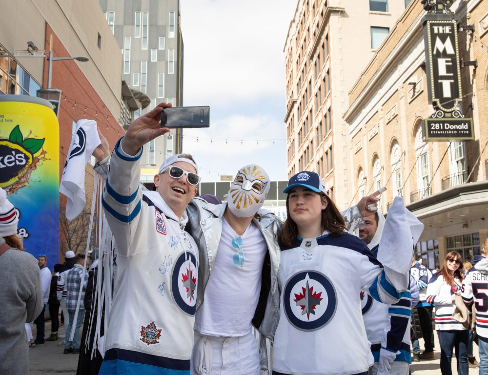 JESSICA LEE / WINNIPEG FREE PRESS
From left: Ryan Anderson, Cameron MacKay and Finlay MacKay pose for a selfie at a Whiteout party. Thousands of Winnipeg Jets fans gathered downtown beside Canada Life Centre April 22, 2023 to watch the Jets play against the Golden Knights.