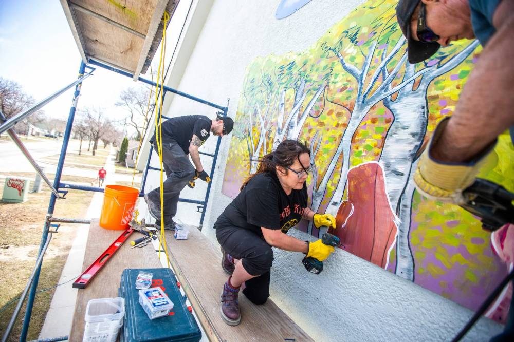 MIKAELA MACKENZIE / WINNIPEG FREE PRESS
Charlie Johnston (left), Jeannie White Bird (middle) and Brad Lent install large mural on the east side of Harrow United Church last week.