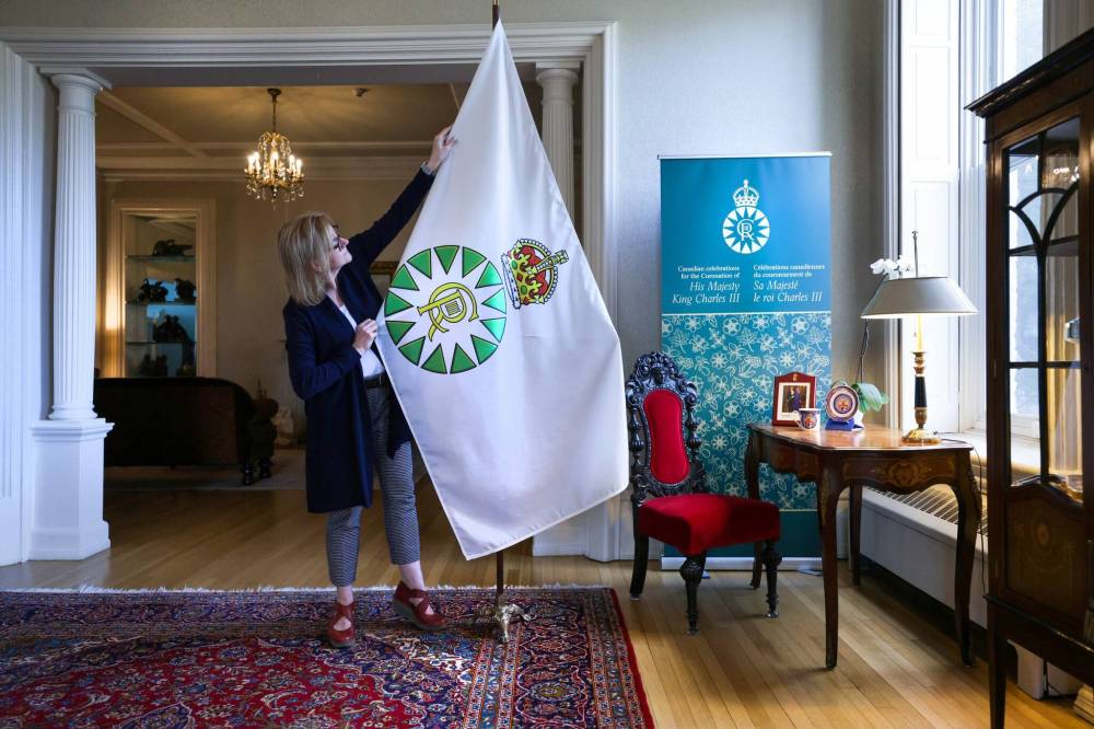 RUTH BONNEVILLE / WINNIPEG FREE PRESS
Kate Gameiro Executive Director of the Lieutenant Governor of Manitoba, adjusts the new Coronation Flag at Manitoba House Wednesday.