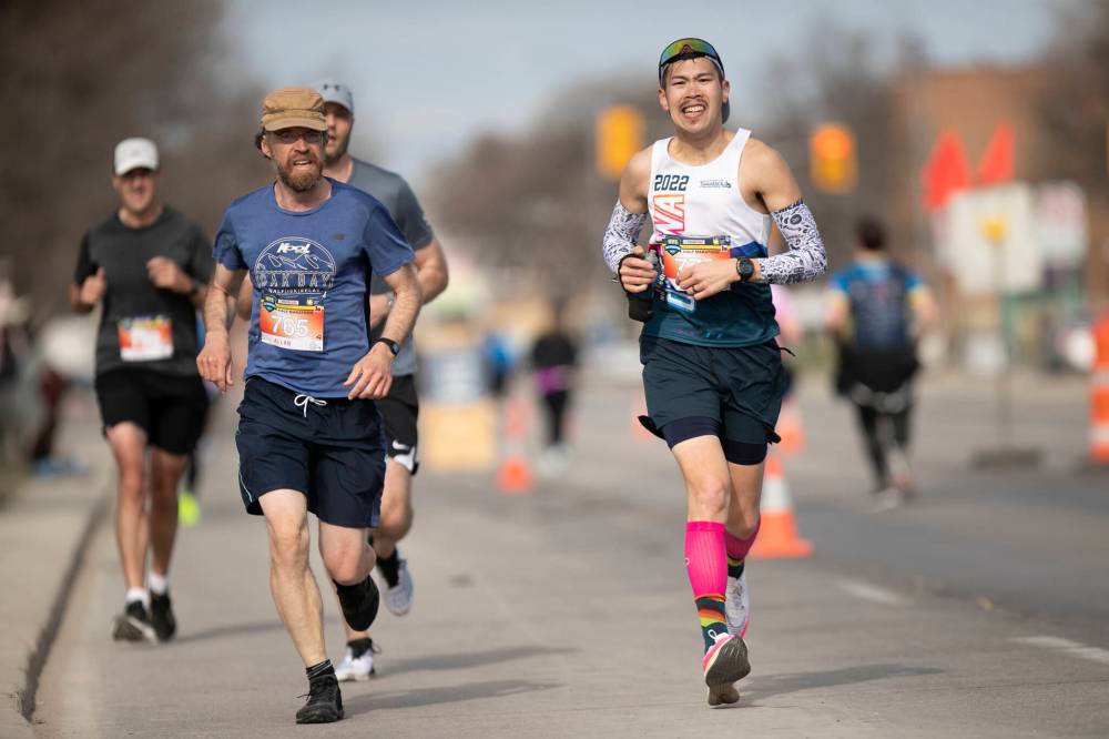 BROOK JONES / WINNIPEG FREE PRESS
                                Runners, including Melvin Yumang (right), head down Portage Avenue with one kilometre left to the finish line during the Winnipeg Police Service Half Marathon on Sunday.