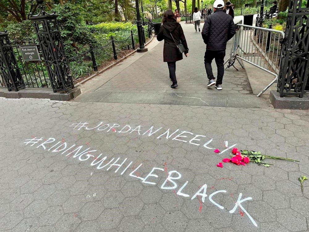 People walk past graffiti calling attention to death of Jordan Neely that was painted on the sidewalk at an entrance to Washington Square Park, Friday, May 5, 2023, in New York. Neely, a locally-known Michael Jackson impersonator who friends say suffered from worsening mental health, died Monday, May 1, when a fellow rider pulled him to the floor and pinned him with a hold taught in Marine combat training. (AP Photo/Brooke Lansdale)