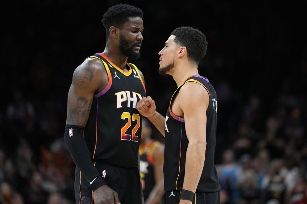 Phoenix Suns guard Devin Booker talks with Phoenix Suns center Deandre Ayton (22) during the first half of Game 4 of an NBA basketball Western Conference semifinal game against the Denver Nuggets, Sunday, May 7, 2023, in Phoenix. (AP Photo/Matt York)