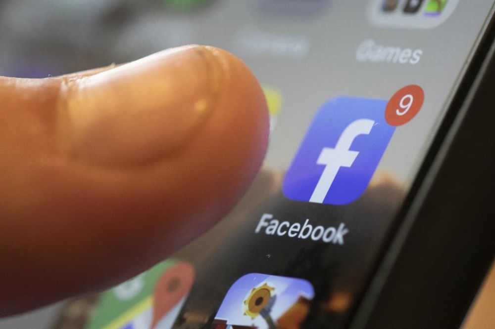 FILE - An iPhone displays the Facebook app in New Orleans, Aug. 11, 2019. Facebook says it is not dead. It’s not even just for “old people,” as young people have been saying for years. The social media platform born before the iPhone is approaching two decades in existence. (AP Photo/Jenny Kane, File)