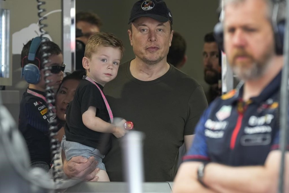 File - Elon Musk holds one of his children as he watches a Red Bull racing crew during practice for the Formula One Miami Grand Prix auto race, at Miami International Autodrome in Miami Gardens, Fla., Saturday, May 6, 2023. Musk said Thursday he has found a new CEO for Twitter, or X Corp. as it’s now called — and it's a woman. He did not name her but said she will be starting in about six weeks. (AP Photo/Rebecca Blackwell, File)