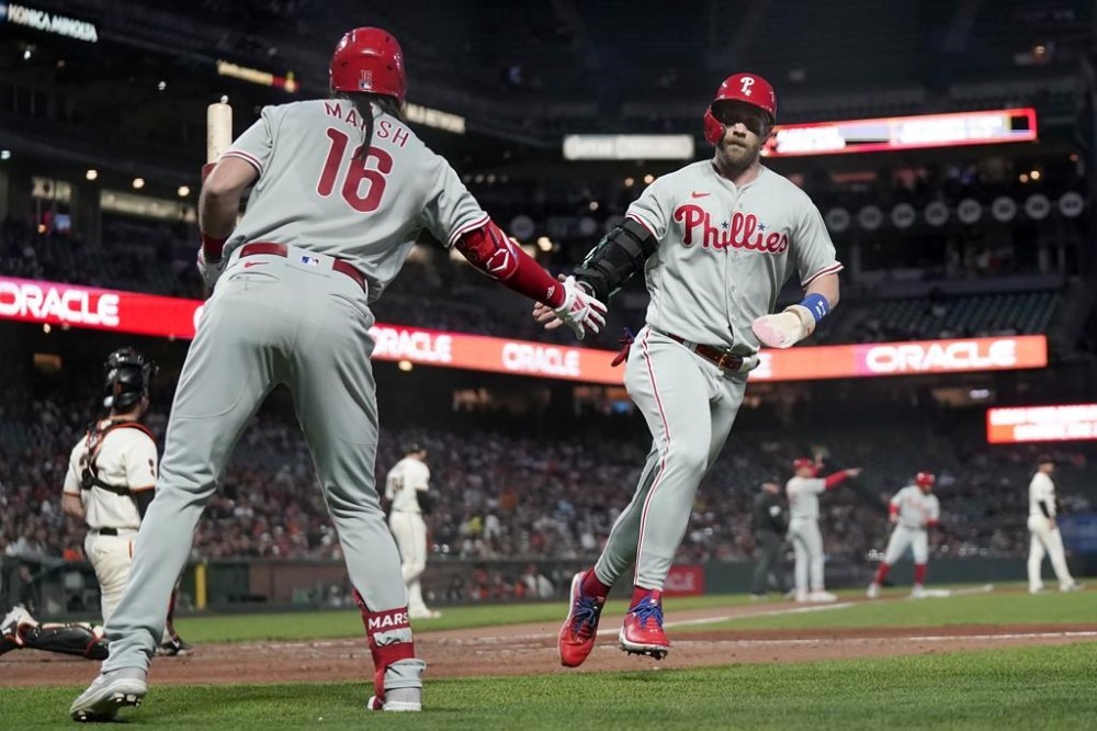 Philadelphia Phillies' Bryce Harper, right, is congratulated by Brandon Marsh (16) after scoring against the San Francisco Giants during the sixth inning of a baseball game in San Francisco, Monday, May 15, 2023. (AP Photo/Jeff Chiu)
