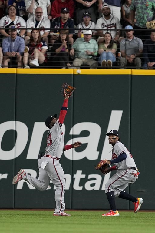 Fans and Atlanta Braves right fielder Ronald Acuna Jr., right, look on as center fielder Michael Harris II positions beneath a fly out hit by Texas Rangers' Jonah Heim in the fourth inning of a baseball game, Tuesday, May 16, 2023, in Arlington, Texas. (AP Photo/Tony Gutierrez)