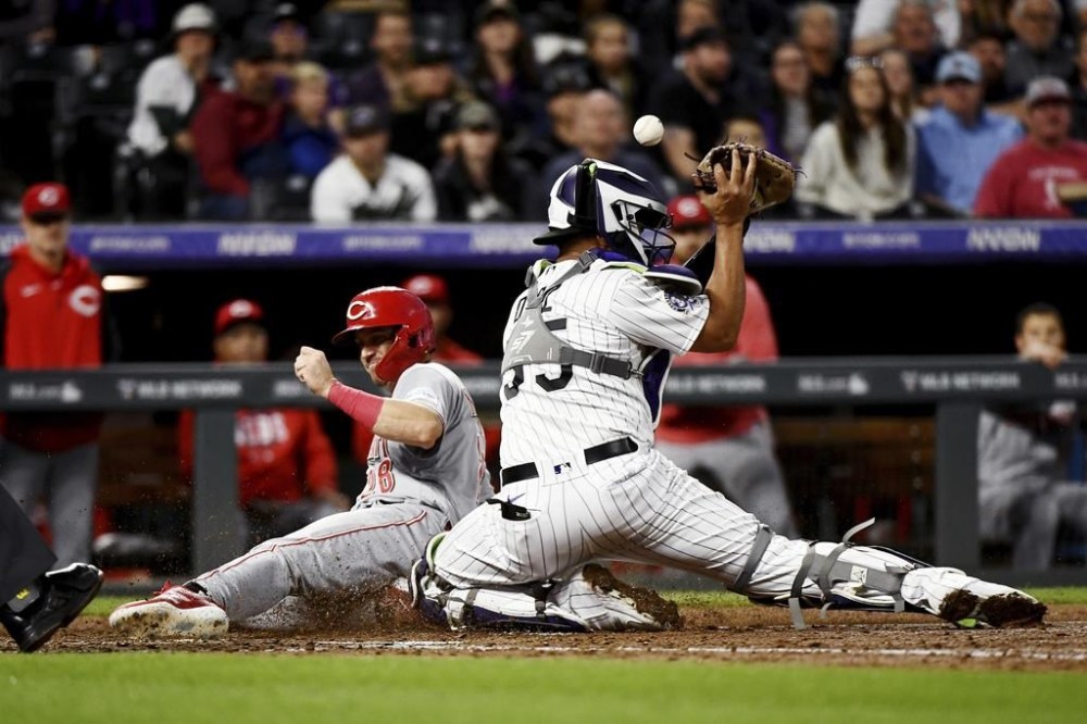 Cincinnati Reds' Kevin Newman slides safely home past Colorado Rockies catcher Elias Diaz in the eighth inning of a baseball game against the Tuesday, May 16, 2023, in Denver. (AP Photo/Geneva Heffernan)