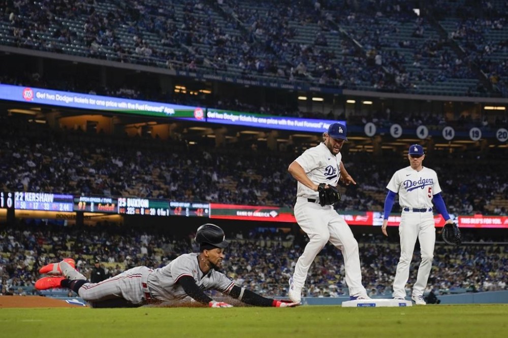 Minnesota Twins designated hitter Byron Buxton, left, reaches first ahead of a throw to Los Angeles Dodgers starting pitcher Clayton Kershaw, center, during the third inning of a baseball game in Los Angeles, Tuesday, May 16, 2023. (AP Photo/Ashley Landis)