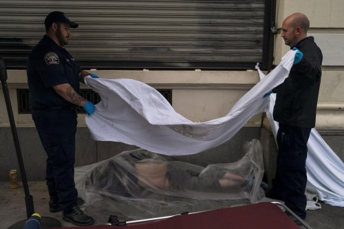 FILE - Forensic assistant Laurentiu Bigu, left, and investigator Ryan Parraz from the Los Angeles County coroner's office cover the body of a homeless man found dead on a sidewalk in Los Angeles on April 18, 2022. The 60-year-old man died from the effects of methamphetamine, according to his autopsy report. Drug overdose deaths in the U.S. went up slightly in 2022 after two big leaps during the pandemic. (AP Photo/Jae C. Hong, File)