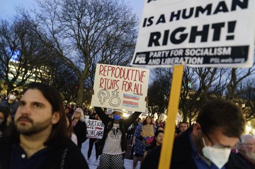 FILE - Tripp Hopkins, center, attends a rally to protest the news that the U.S. Supreme Court could be poised to overturn the landmark Roe v. Wade case that legalized abortion nationwide, May 3, 2022, at the Statehouse in Providence, R.I. On June 24, the Supreme Court overturned Roe v. Wade. The Rhode Island Senate is set to vote Thursday, May 18, 2023, on a measure that would allow state funds to be used to pay for health plans that cover state workers and Medicaid recipients seeking abortions. (AP Photo/David Goldman, File)