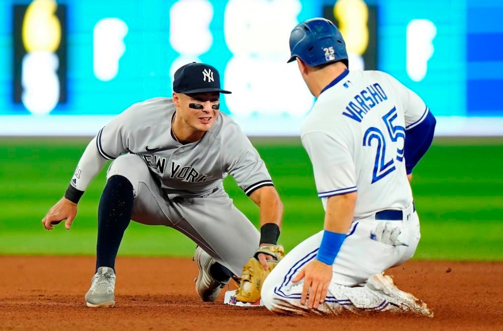 New York Yankees shortstop Anthony Volpe (11) tags out Toronto Blue Jays' Daulton Varsho (25) trying to steal second base during fourth inning MLB American League baseball action in Toronto, on Thursday, May 18, 2023. THE CANADIAN PRESS/Frank Gunn