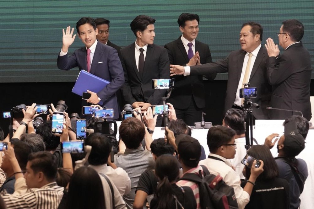 Leader of Move Forward Party Pita Limjaroenrat, left, waves after signing a memorandum of understanding on attempt to form a coalition government between Move Forward Party and other parties during a news conference in Bangkok, Thailand, Monday, May 22, 2023. Move Forward won the most seats in the May 14 election, and it has formed a coalition that seeks to become the government when Parliament selects a prime minister in July. (AP Photo/Sakchai Lalit)