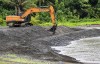 An excavator operator constructs a double berm along the shoreline of the Umatac Bay, near the mouth on the Laelae River, Guam as part as storm mitigation measures as Typhoon Mawar approaches the region Tuesday, May 23, 2023. (Rick Cruz/The Pacific Daily via AP)