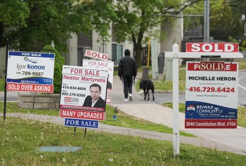 Canada Mortgage and Housing Corp. says the country's residential mortgage debt increased six per cent from last year to $2.08 trillion. A person walks past multiple for-sale and sold real estate signs in Mississauga, Ont., on Wednesday, May 24, 2023. THE CANADIAN PRESS/Nathan Denette