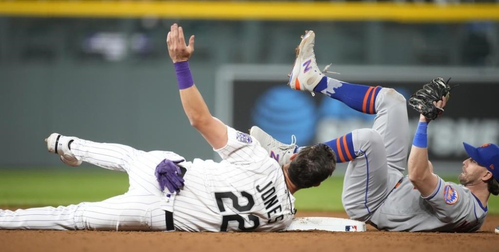 New York Mets second baseman Jeff McNeil, right, tumbles after tagging out Colorado Rockies' Nolan Jones, left, at second base as Jones tried to advance on a ground ball in the ninth inning of a baseball game Friday, May 26, 2023, in Denver. (AP Photo/David Zalubowski)