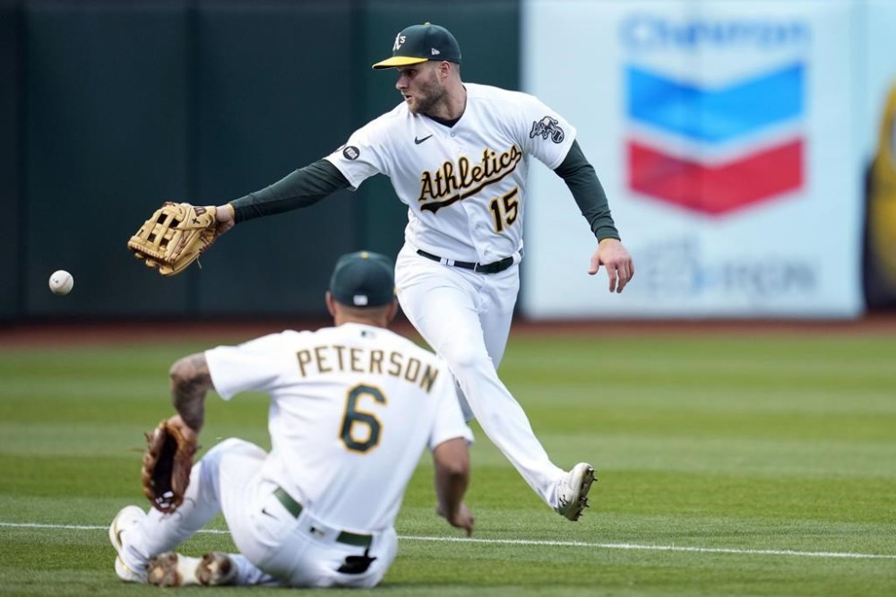 Oakland Athletics left fielder Seth Brown (15) and third baseman Jace Peterson, foreground, are unable to make the play on a single by Houston Astros' Kyle Tucker during the third inning of a baseball game in Oakland, Calif., Friday, May 26, 2023. (AP Photo/Godofredo A. Vásquez)