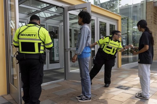Security guards check identification for proof of age outside the Mall in Columbia, Friday, May 12, 2023, in Columbia, Md. The mall has implemented a 