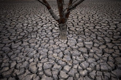 FILE - Cracked earth is visible after the water level has dropped in the Sau reservoir north of Barcelona, Spain, April 18, 2023. Europe's largest desalination plant for drinking water had largely remained idle since its construction near Barcelona over a decade ago. But since a prolonged drought gripped Spain, the plant has been running at full throttle. (AP Photo/Emilio Morenatti, File)