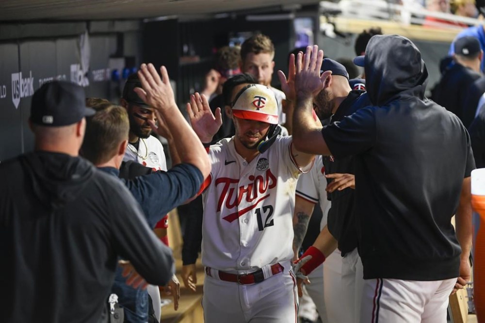 Minnesota Twins' Kyle Farmer (12) celebrates in the dugout after scoring on a double by Jorge Polanco against the Cleveland Guardians during the seventh inning of a baseball game, Friday, June 2, 2023, in Minneapolis. (AP Photo/Craig Lassig)