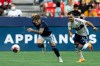 Sporting Kansas City's Marinos Tzionis (77) and Vancouver Whitecaps' Luís Martins (14) chase the ball during the first half of an MLS soccer match in Vancouver, on Saturday, June 3, 2023. THE CANADIAN PRESS/Ethan Cairns
