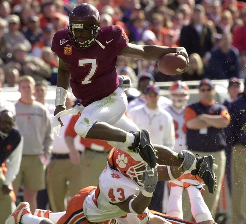 FILE - Virginia Tech quarterback Michael Vick (7) eludes Clemson's Keith Adams for a short gain in the first quarter of the Gator Bowl in Jacksonville, Fla., Monday, Jan. 1, 2001. Michael Vick, Larry Fitzgerald and Terrell Suggs are among the college football stars who will be considered for induction to the Hall of Fame for the first time this year. The National Football Foundation released Monday, June 5, 2023, a list of 78 players and nine coaches from major college football who are on the Hall of Fame ballot.(AP Photo/Steve Helber, File)