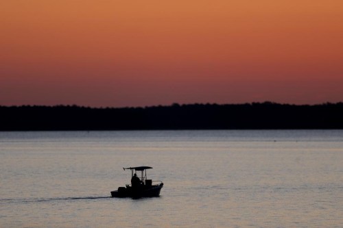 FILE - A small boat travels along the Honga River near the Chesapeake Bay, as the sky lights up at sunrise in Fishing Creek, Md., May 14, 2020. A report on the Chesapeake Bay released Tuesday, June 6, 2023, found strong disparities between communities in different parts of the bay's watershed in terms of health, economics and social justice concerns, presenting the challenges of improving the health of the nation's largest estuary in a larger context. (AP Photo/Julio Cortez, File)