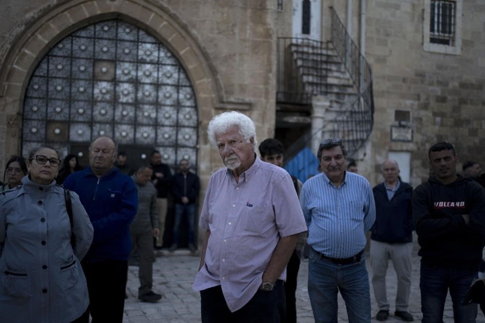 Garo Nalbandian, an 80-year-old photojournalist, center, listens to a speaker during an Armenian community protest of a contentious deal that stands to displace him and other residents and cede some 25 percent of the Armenian Quarter in the Old City of Jerusalem, Friday, May 19, 2023.