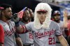 FILE - Washington Nationals Corey Dickerson (23), wearing a powdered wig while holding a tiny American flag, is congratulated in the dugout after hitting a two-run home run against the Miami Marlins, Wednesday, May 17, 2023, in Miami. About half the clubs in MLB are using some kind of prop or ritual to celebrate a big hit or a big play in ways that often go viral. (AP Photo/Marta Lavandier, File)