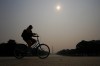 A cyclist rolls under haze blanketing over the Reflecting Pool with the Washington Monument seen at a distance, Wednesday, June 7, 2023, in Washington. Intense Canadian wildfires are blanketing the northeastern U.S. in a dystopian haze, turning the air acrid, the sky yellowish gray and prompting warnings for vulnerable populations to stay inside. (AP Photo/Julio Cortez)