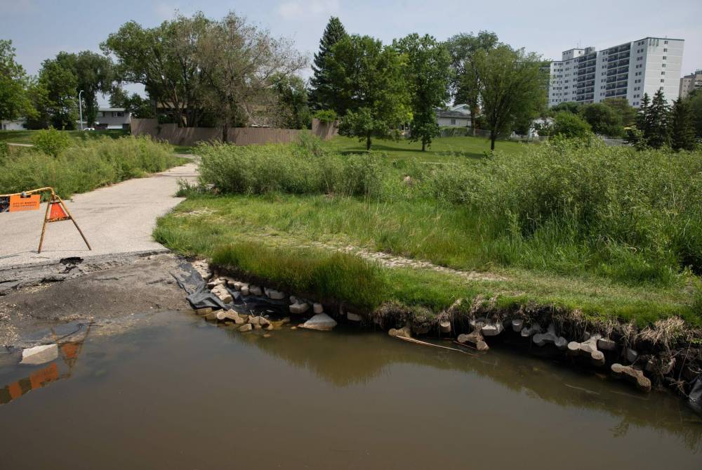 JESSICA LEE / WINNIPEG FREE PRESS
A massive, water-filled hole where the busy Sturgeon Creek active transportation route meets a playground path has posed a safety hazard for several weeks.