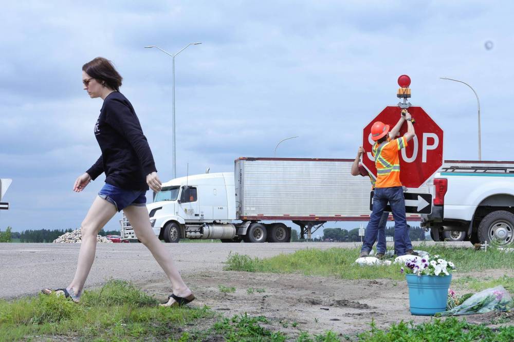 A woman drops off a bouquet of flowers Friday at a memorial at the intersection of Highway 1 and Highway 5. (Ruth Bonneville / Winnipeg Free Press)