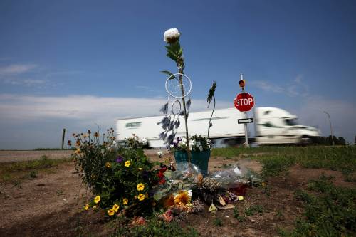 A semi-trailer passes by flowers and other items placed at the intersection of the Trans-Canada Highway and Highway 5 just north of Carberry as a memorial to the victims of last week&rsquo;s collision involving a semi-trailer and a passenger bus. (Tim Smith / The Brandon Sun files)