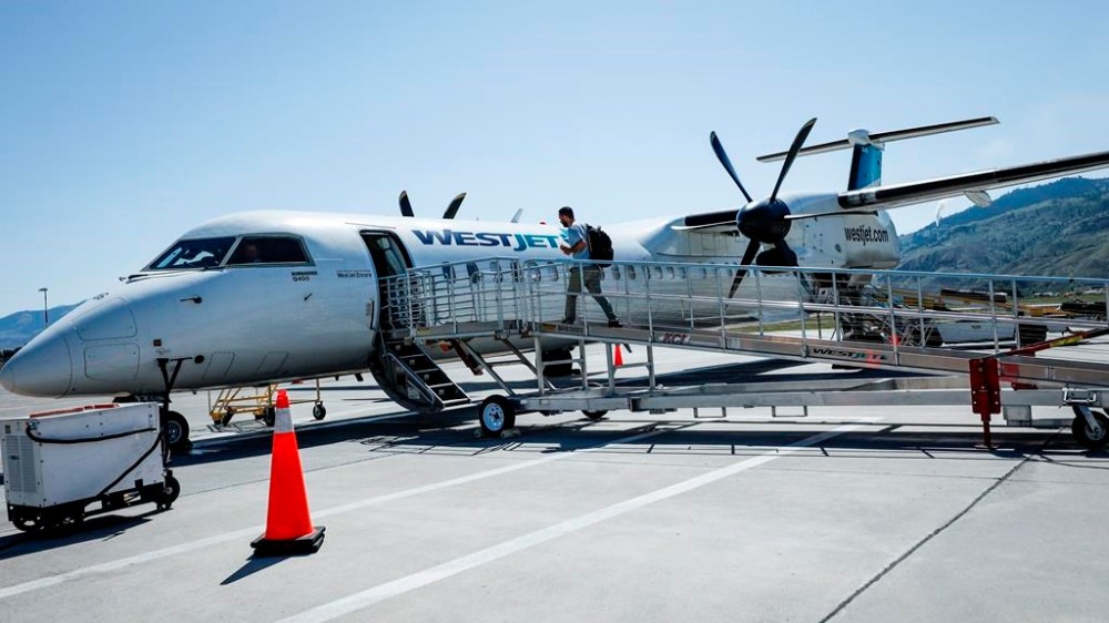 A passenger boards a WestJet Encore Bombardier Q400 twin-engined turboprop aircraft in Kamloops, Saturday, June 3, 2023. WestJet and Swoop pilots ratified their collective agreement after a bargaining process that saw the threat of a strike snarl many Canadians' long weekend plans. THE CANADIAN PRESS/Jeff McIntosh