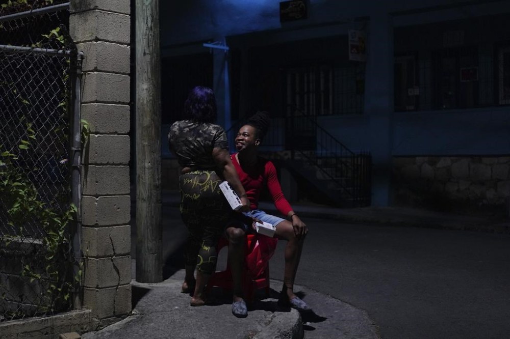 Orden David talks with a local sex worker he is friendly with while distributing condoms and lubricant to the women, early Saturday, May 13, 2023, in St. John's, Antigua. (AP Photo/Jessie Wardarski)